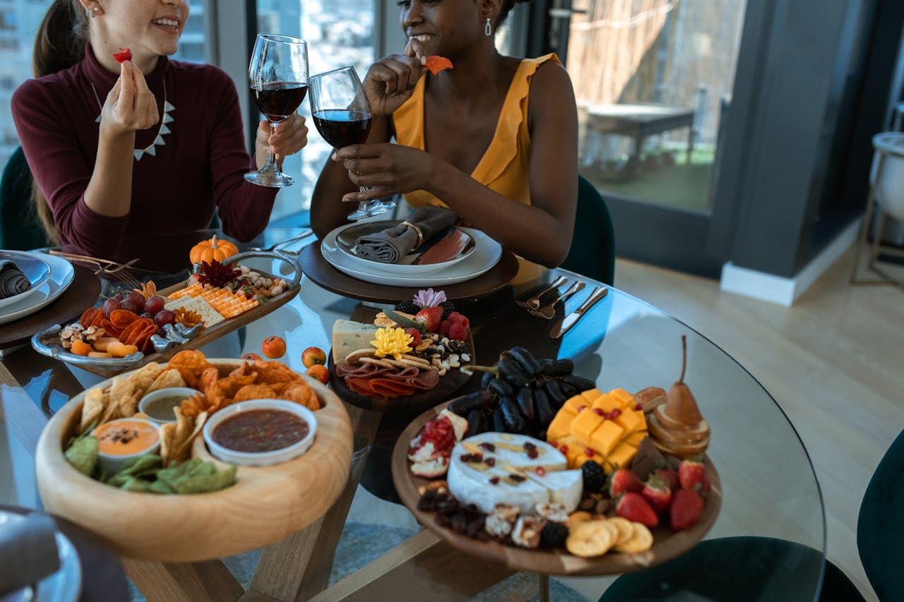 Two adults enjoy wine and a colorful charcuterie board indoors, embodying warmth and friendship.